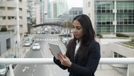 Serious-businesswoman-using-tablet-pc-on-bridge