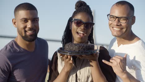 Laughing-young-people-posing-with-brown-cake.