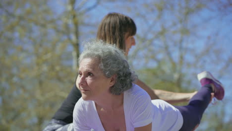 Focused-senior-woman-training-in-park-with-trainer.