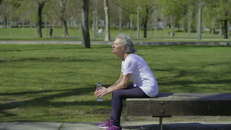 Tired-elderly-woman-resting-after-workout-in-park