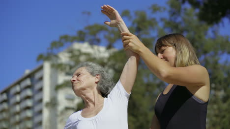 Smiling-elderly-lady-stretching-arms-before-training.