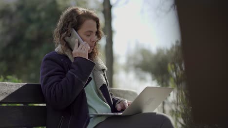 Thoughtful-middle-aged-woman-talking-on-smartphone-outdoor