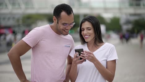 Smiling-friends-talking-while-looking-at-smartphone