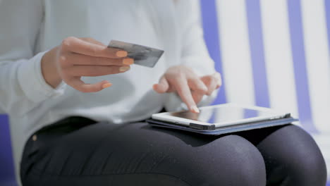 Girl-holding-credit-card-and-using-tablet-pc