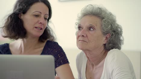 Two-smiling-women-using-laptop-at-home.