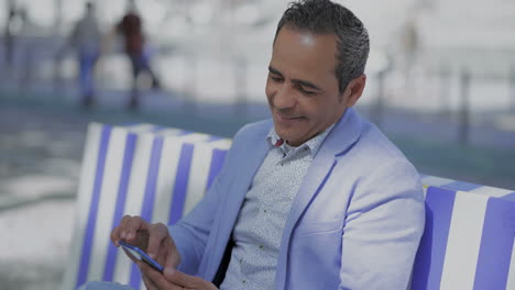 Lächelnder-Hispanischer-Mann,-Der-Sein-Smartphone-Im-Freien-Benutzt