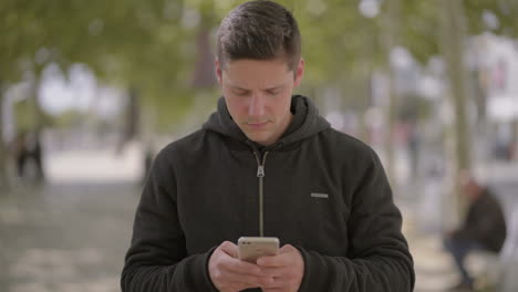 Focused-man-walking-with-smartphone-on-street