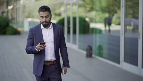 Serious-businessman-with-laptop-and-smartphone-outdoor