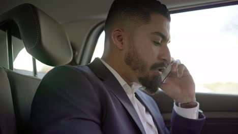 Focused-businessman-talking-by-cell-phone-in-car
