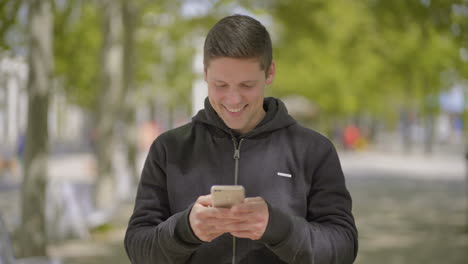 Smiling-young-man-using-mobile-phone-outdoor
