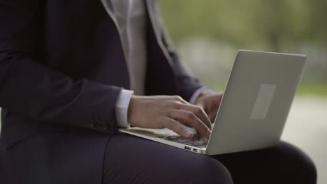 Businessman-typing-on-laptop-computer-outdoor