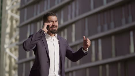 Emotional-businessman-talking-by-smartphone-and-gesturing