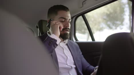 Businessman-answering-phone-call-in-car