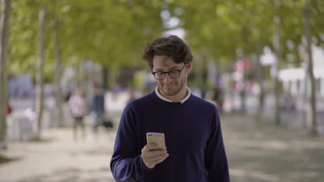 Smiling-man-using-mobile-phone-outdoor