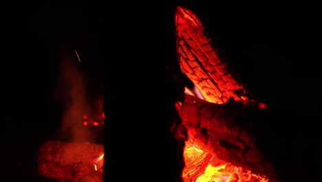 Pink-flames-dance-between-red-and-yellow-glowing-embers-and-fire-cracked-logs