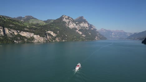 Aerial-view-of-a-boat-traveling-down-a-water-strait-through-the-mountains-in-Switzerland