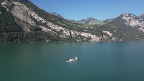 Wide-aerial-view-of-boat-traveling-across-the-water-at-the-base-of-a-beautiful-mountain-range