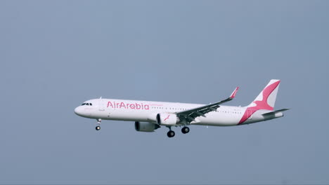 Air-Arabia-Con-Las-Ruedas-Abajo-Volando-Hacia-La-Izquierda-Pasando-Por-Una-Torre-De-Control-De-Tráfico-Aéreo-En-El-Aeropuerto-De-Suvarnabhumi-En-Bangkok.