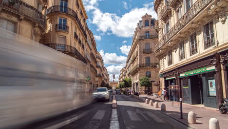 Traffic-driving-the-Rue-Foch-in-Montpellier,-people-walking-along-sidewalks