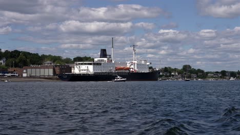 State-of-Maine-open-ocean-ship-docked-at-pier-as-smaller-boat-circles