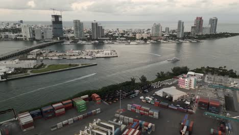 Aerial-skyline-cityscape-at-sunset-revealing-commercial-port-with-cargo-crane-containers-and-cityscape-downtown-near-south-beach