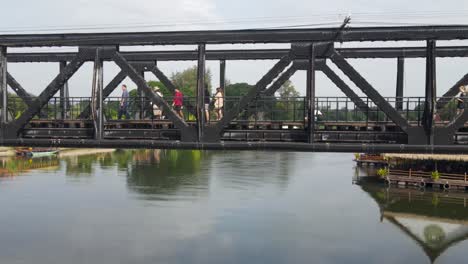 Die-Nach-Rechts-Gleitende-Drohne-Zeigt-Menschen,-Die-Die-River-Kwai-Gedenkbrücke-überqueren-Und-Sich-Neugierig-In-Diesem-Museum-Des-Zweiten-Weltkriegs-In-Kanchanaburi,-Thailand,-Umsehen