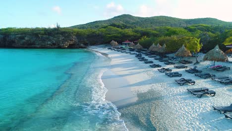 Grote-Knip-Curacao-white-sandy-beach-with-lounge-chairs-set-up-in-perfect-row,-aerial-side-dolly