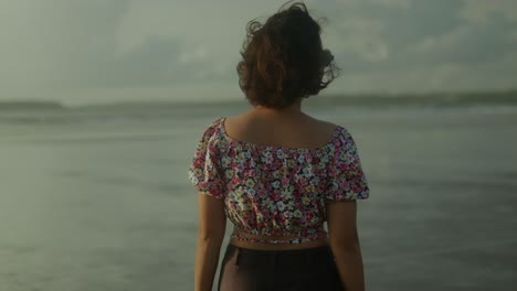 Back-View-of-a-beautiful-carefree-young-girl-slowly-walking-on-a-sea-coast