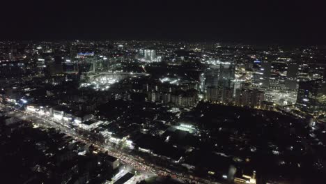 In-the-Hyderabad-City-Centre,-Hitech-City-Road-can-be-seen-from-above-being-surrounded-by-skyscrapers-with-flashing-lights-and-busy-traffic-at-night