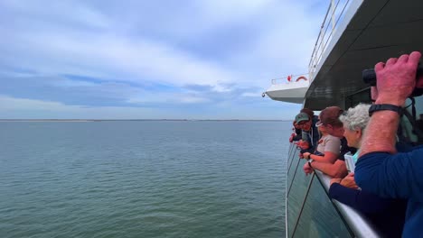 Pasajeros-Del-Ferry-Observando-La-Costa-Norte-Y-Del-Mar-De-Wadden-Con-Binoculares