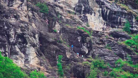 A-group-of-climbers,-wearing-safety-harnesses-and-helmets,-trying-to-climb-up-the-via-ferrata-in-the-Passeier-Valley,-South-Tyrol,-Italy
