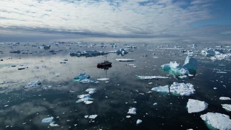 Transportation-ship-sailing-near-icebergs-in-deep-ocean,-aerial-view