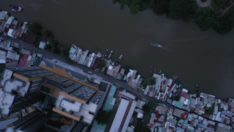 Top-down-Aerial-view-on-Kenh-Te-canal-Ho-Chi-Minh-City-with-old-iron-and-wood-shacks,-traditional-river-boats-and-ultra-modern-high-rise-buildings-and-landscaped-park