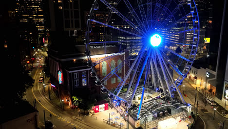 Luftaufnahme-Des-Beleuchteten-Riesenrads-Namens-Skywatch,-Das-Sich-Nachts-In-Der-Stadt-Atlanta-Dreht-–-Wunderschöne-Stadt-Im-Hintergrund