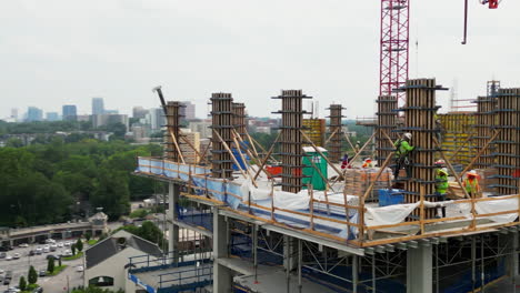 Aerial-slide-and-pan-footage-of-construction-workers-performing-dangerous-tasks-high-above-ground