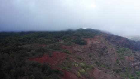 Aerial-low-rising-shot-into-low-lying-clouds-on-a-mountain-road-near-Waimea-Canyon-in-Kaua'i,-Hawai'i