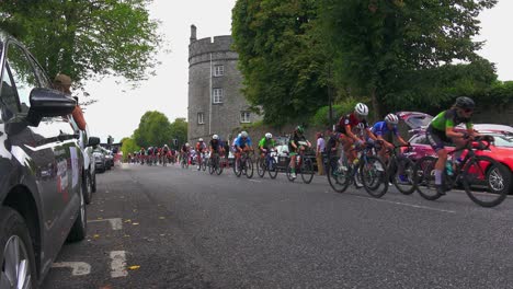 Carrera-Ciclista-Femenina-Pasando-El-Castillo-De-Kilkenny,-Irlanda,-En-Un-Cálido-Día-De-Otoño