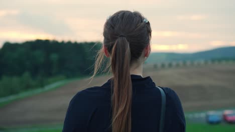 Young-woman-in-the-countryside-stands-and-looks-out-contemplating-her-future