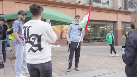 Junger-Mann-Hält-Die-Flagge-Kurdistans,-Während-Freunde-Fotos-Für-Soziale-Medien-Machen