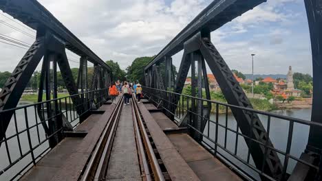 Timelapse-view-of-the-famous-Bridge-on-the-River-Kwai-in-Kanchanaburi,-Thailand-as-many-tourists-walk-along-and-explore-this-landmark