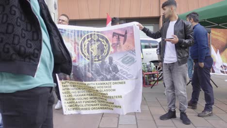 Junge-Männliche-Demonstranten-Protestieren-Mit-Einem-Großen-Plakat-Gegen-Die-Iranische-Regierung