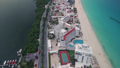 Vista-Aérea-De-Los-Hoteles-Y-Complejos-Turísticos-De-Cancún-Con-Una-Inclinación-Hacia-Arriba-Que-Revela-La-Pintoresca-Playa-Con-Aguas-Turquesas-Que-Se-Extienden-Hasta-El-Horizonte-En-México