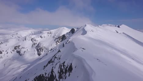 Wunderschöne-Schneebedeckte-Berggipfel-Und-Bergrücken-Mit-Einem-Gesims-Aus-Weißem-Schnee,-Das-über-Dem-Felsvorsprung-Hängt