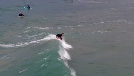 Vista-Aérea-En-Cámara-Lenta-De-Un-Solo-Surfista-Montando-Una-Ola-En-La-Playa-De-Malibu