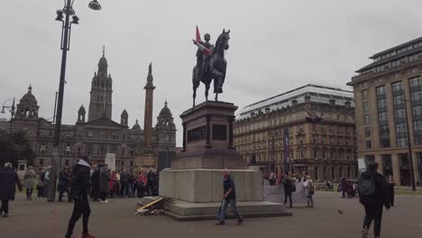 People-walk-past-the-statue-of-Queen-Victoria-with-two-cones