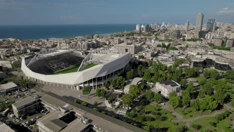 Revealing-tel-aviv-skyline-and-Bloomfield-football-Stadium-from-a-drone,-the-Stadium-hosted-musical-acts-from-time-to-time-and-It-is-the-home-of-three-soccer-clubs