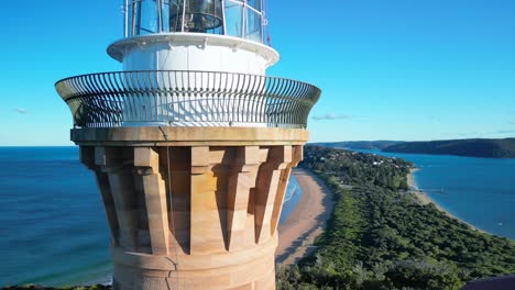 Drone-ascends-at-Barrenjoey-Lighthouse-to-reveal-stunning-summer-day-with-crystal-clear-blue-water-at-Palm-Beach-near-Sydney,-Australia