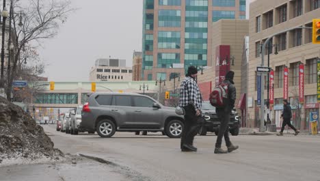 Una-Acera-Nublada-Toma-De-Tráfico-De-Automóviles-Ocupado-En-Winnipeg-Gente-Ciudadanos-Ruta-85-Avenida-Portage-Calle-Principal-En-El-Centro-De-La-Ciudad-Centro-De-Vida-De-Canadá-Primavera-Nieve-Canadá-2023