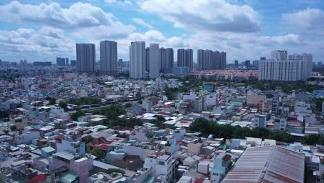 Die-Drohne-Neigt-Sich-Von-Den-Dächern-Des-Dicht-Besiedelten-Industrie--Und-Wohngebiets-Von-Ho-Chi-Minh-Stadt-In-Vietnam-Zu-Einem-Weiten-Panorama-Mit-Modernen-Wohnhochhäusern-Und-Einer-Hauptstraße-Mit-Blauem-Himmel