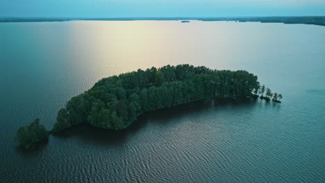 High-angle-shot-of-a-small-island-or-isle-on-a-lake-in-southern-Finland,-setting-sun-is-reflected-on-the-water